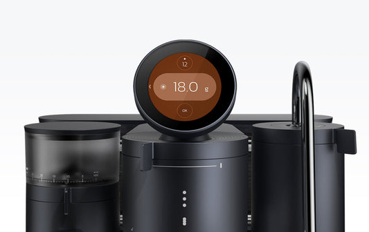 Close-up of the smart espresso machine's circular digital display showing the coffee dose setting of 18.0 grams, with the integrated grinder visible on the left.