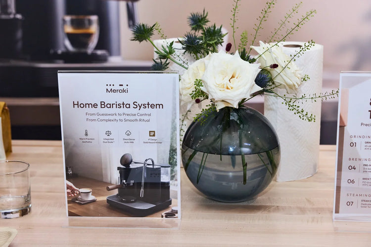 Meraki Home Barista System information card beside white flowers on the event counter.