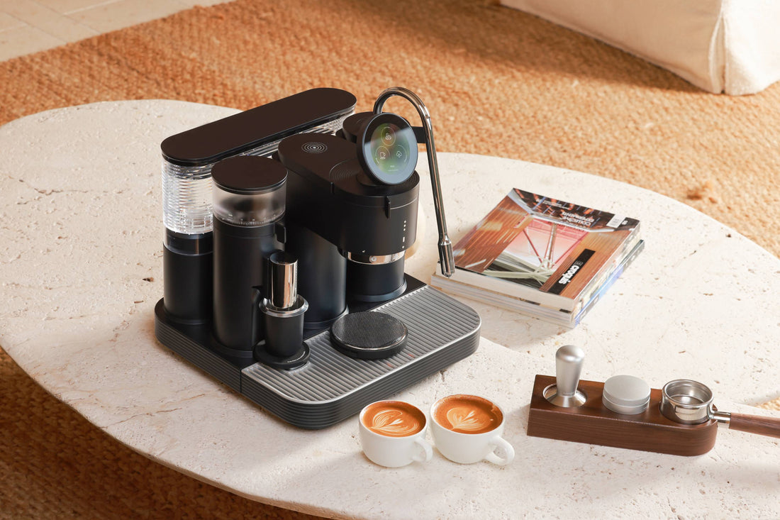 Sleek and modern coffee maker with various accessories on a marble countertop, including cups with latte art, a grinder, and other barista tools. The image showcases a high-end, stylish coffee brewing setup.