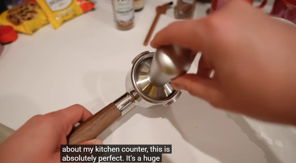 Tamping ground coffee in a wooden-handled Meraki portafilter during Jeff Springer’s review.