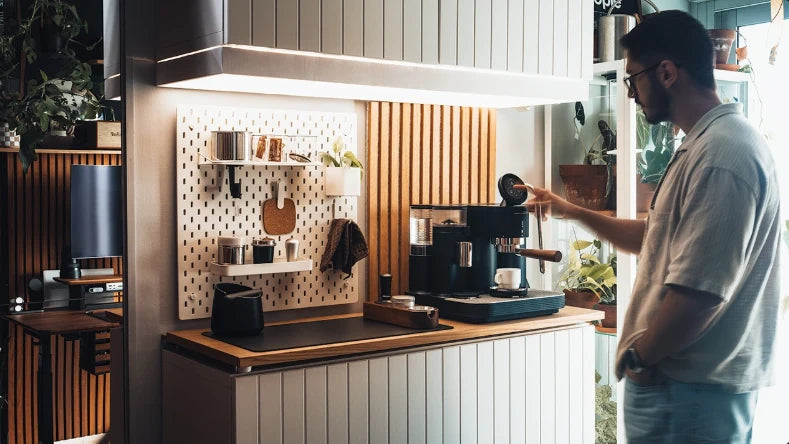 Mattia Di Lisio using the Meraki touchscreen at his home office coffee bar with pegboard storage and overhead lighting.