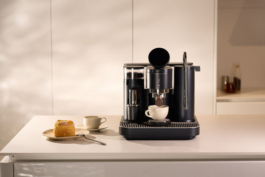 Coffee beans and an espresso cup beside the Meraki Espresso Machine