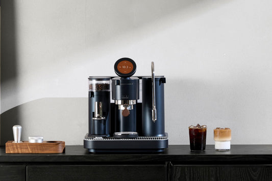 Meraki espresso machine on a kitchen counter with two espresso drinks and a minimalist background