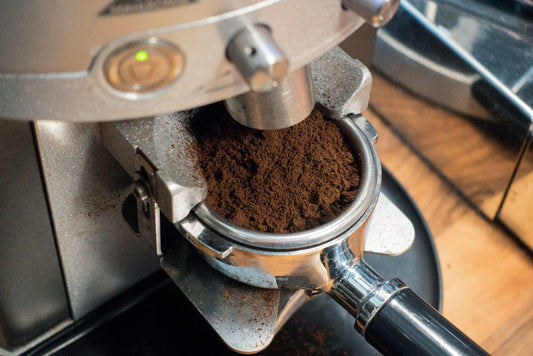 Fresh espresso grounds dispensing from a coffee grinder into a portafilter