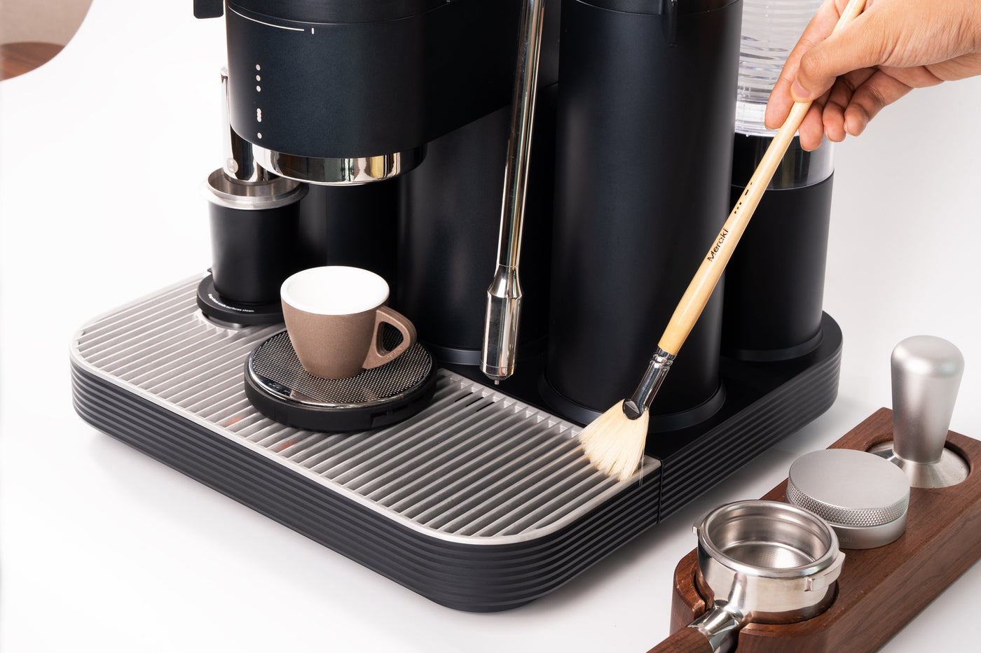White semi-automatic espresso machine with integrated grinder and steam wand being cleaned on a kitchen counter