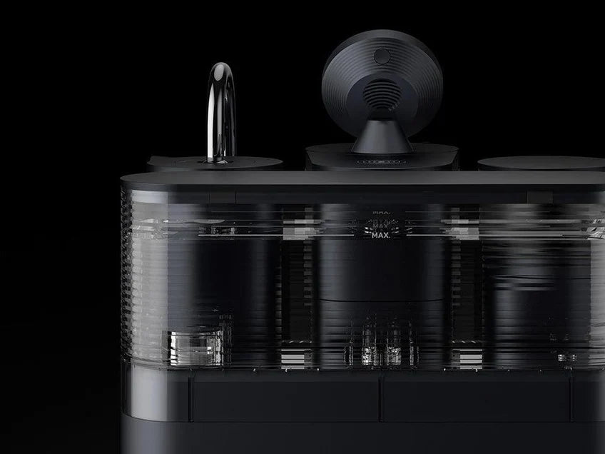 Rear view of a black Meraki espresso machine showing the transparent water reservoir and maximum fill markings