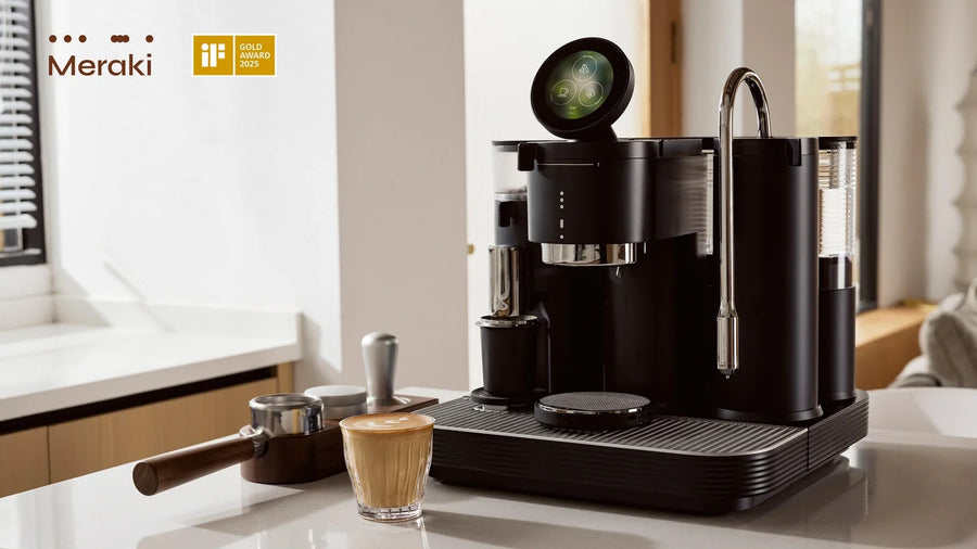 Black Meraki espresso machine on a kitchen island beside a latte and portafilter, with the iF Gold Award 2025 badge