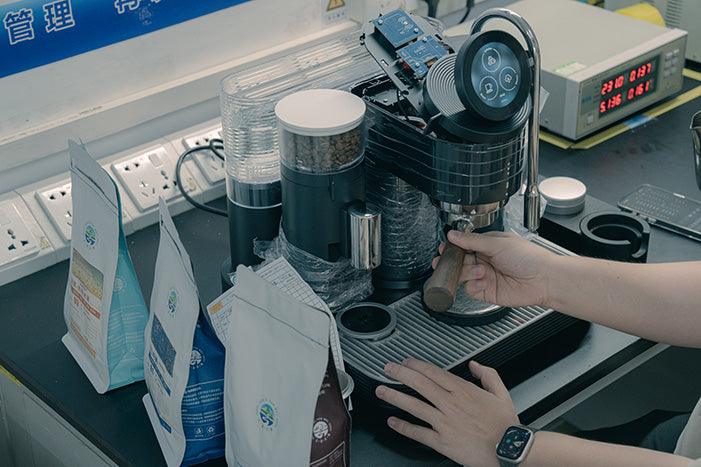 Hands fitting a portafilter into a Meraki espresso machine prototype on a development workbench
