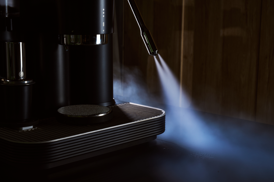 Steam rising from the steam wand of a black Meraki espresso machine