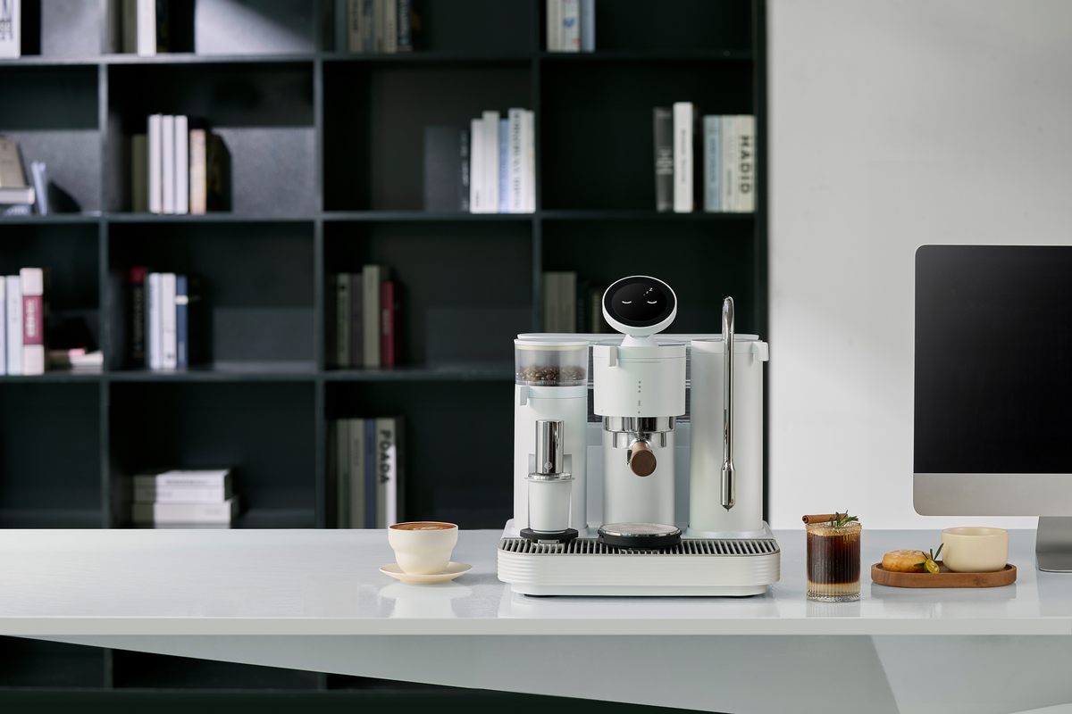 White Meraki espresso machine in front of a bookshelf