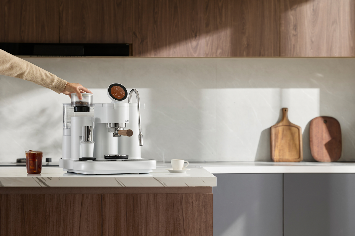 Using the touchscreen of a white Meraki espresso machine in a kitchen