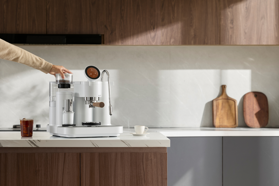 Using the touchscreen of a white Meraki espresso machine in a kitchen