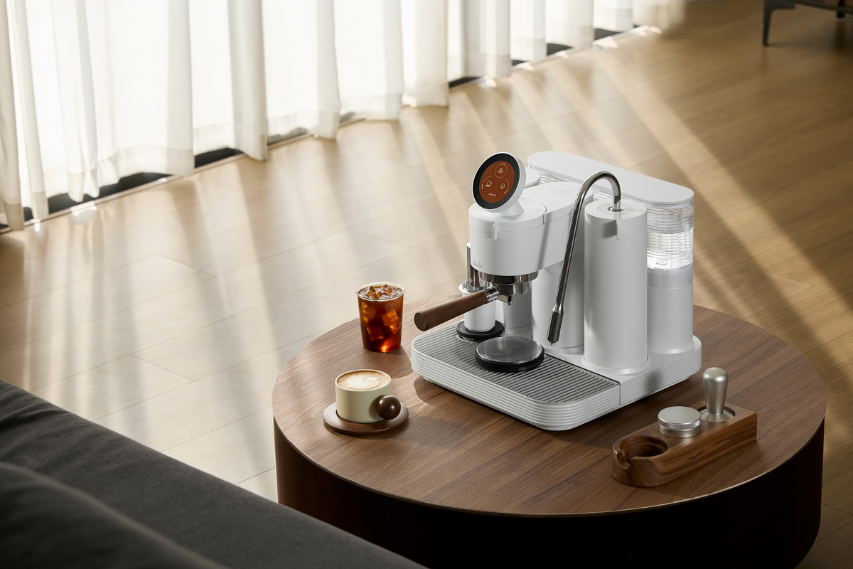 White Meraki espresso machine with coffee on a round wooden table