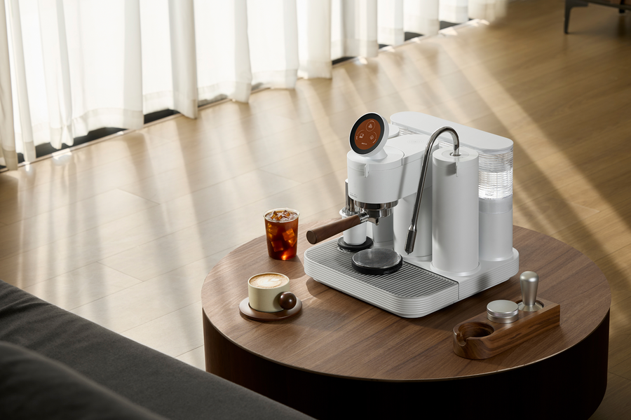 White Meraki espresso machine with coffee on a round wooden table