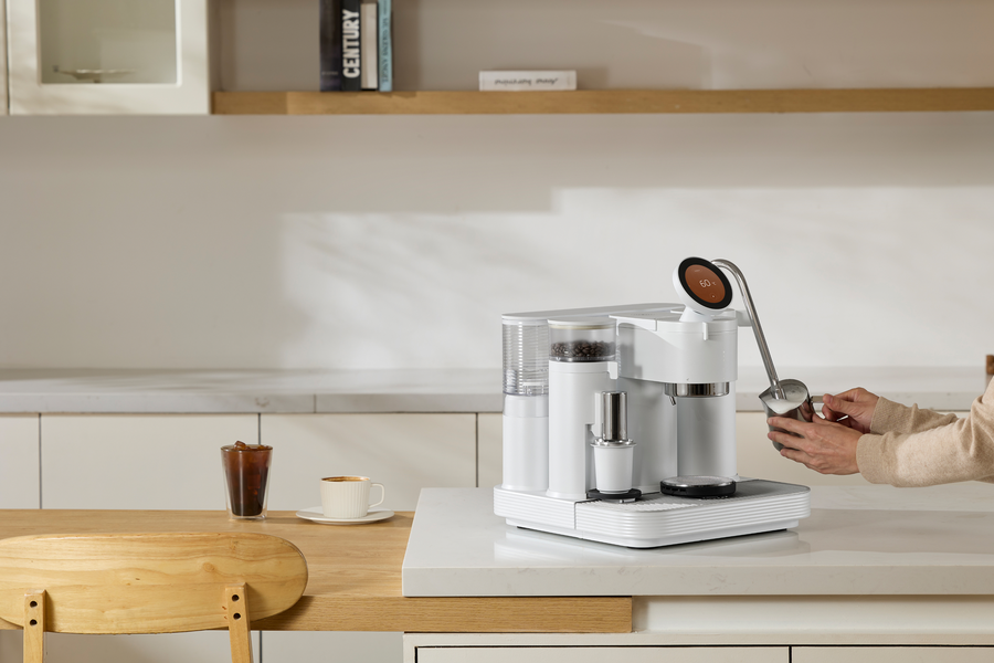 Steaming milk with a white Meraki espresso machine on a kitchen counter