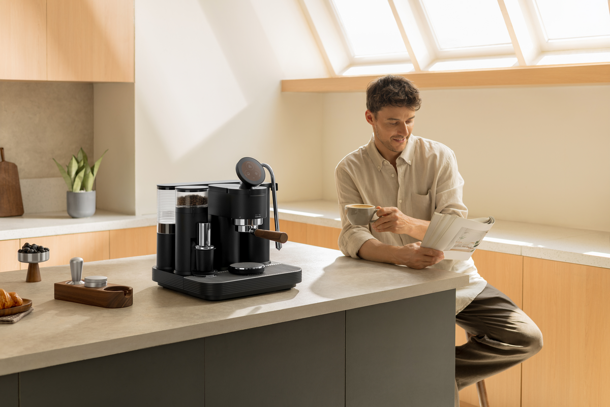 Enjoying coffee beside a black Meraki espresso machine on a kitchen island