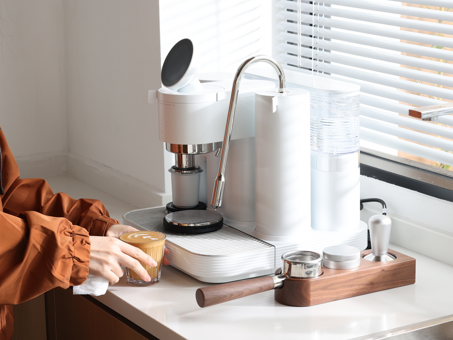 Preparing espresso at a wooden coffee station with a white Meraki machine