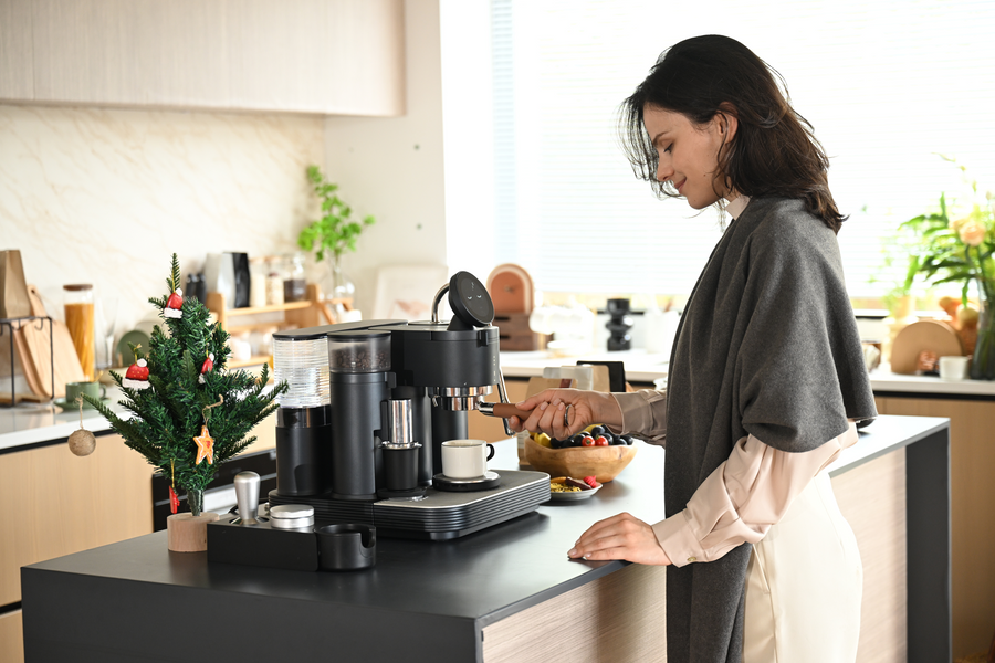 Preparing coffee with a black Meraki espresso machine in a bright kitchen