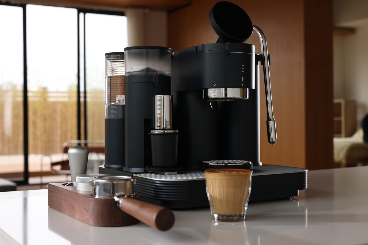 Black Meraki espresso machine with a prepared latte beside a window