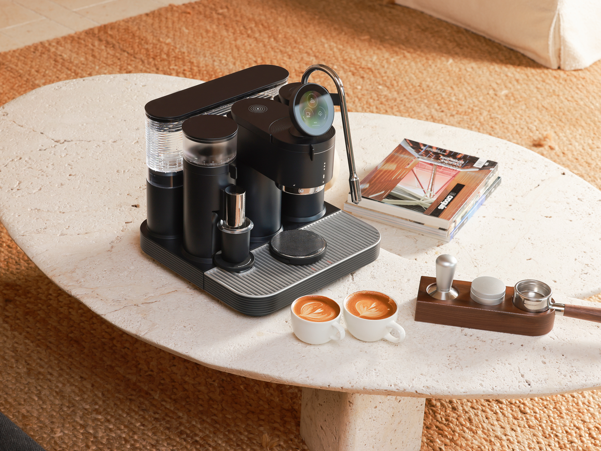 Black Meraki espresso machine with two espresso cups and coffee accessories