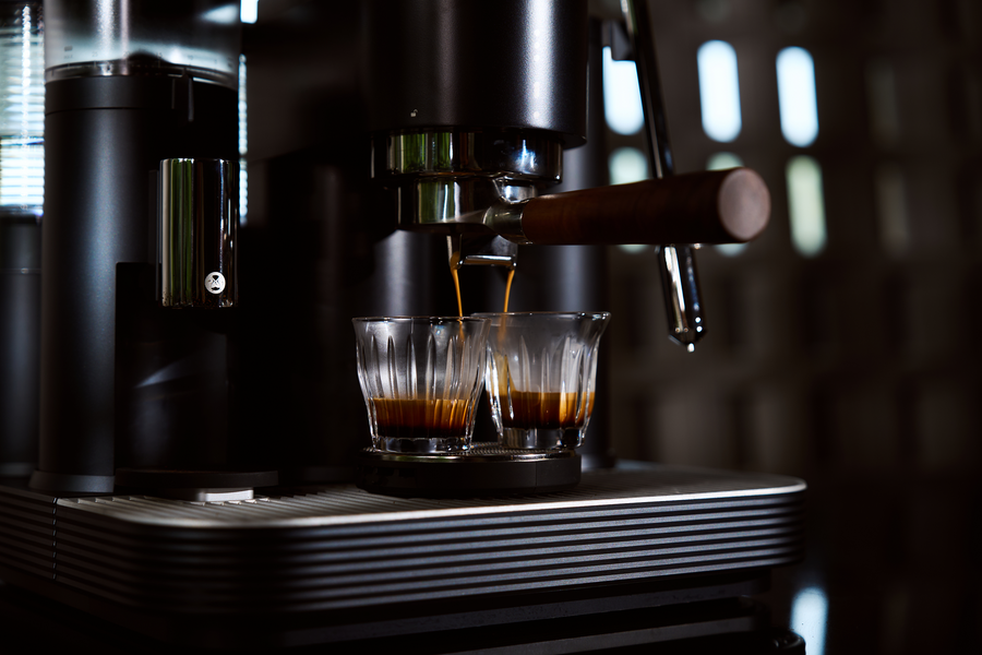 Espresso pouring into two clear glasses from a black Meraki espresso machine