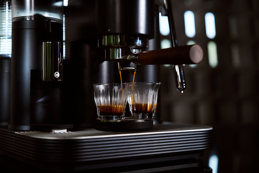 Espresso pouring into two clear glasses from a black Meraki espresso machine