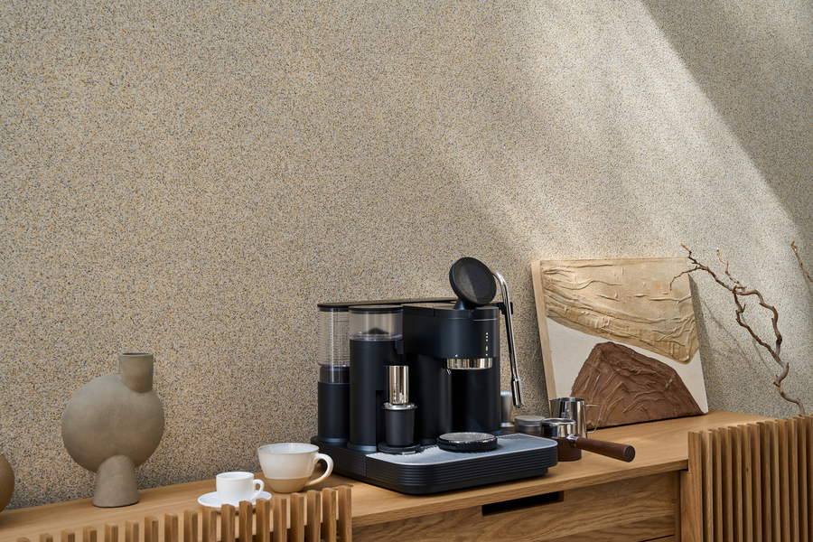 Black Meraki espresso machine on a wooden console beside a vase