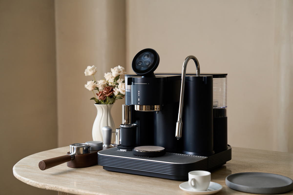Black Meraki espresso machine on a coffee table beside flowers