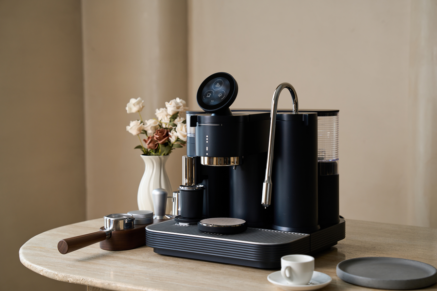 Black Meraki espresso machine on a coffee table beside flowers