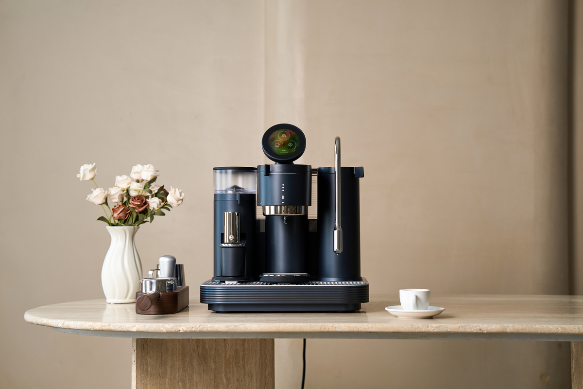 Black Meraki espresso machine on an oval wooden table