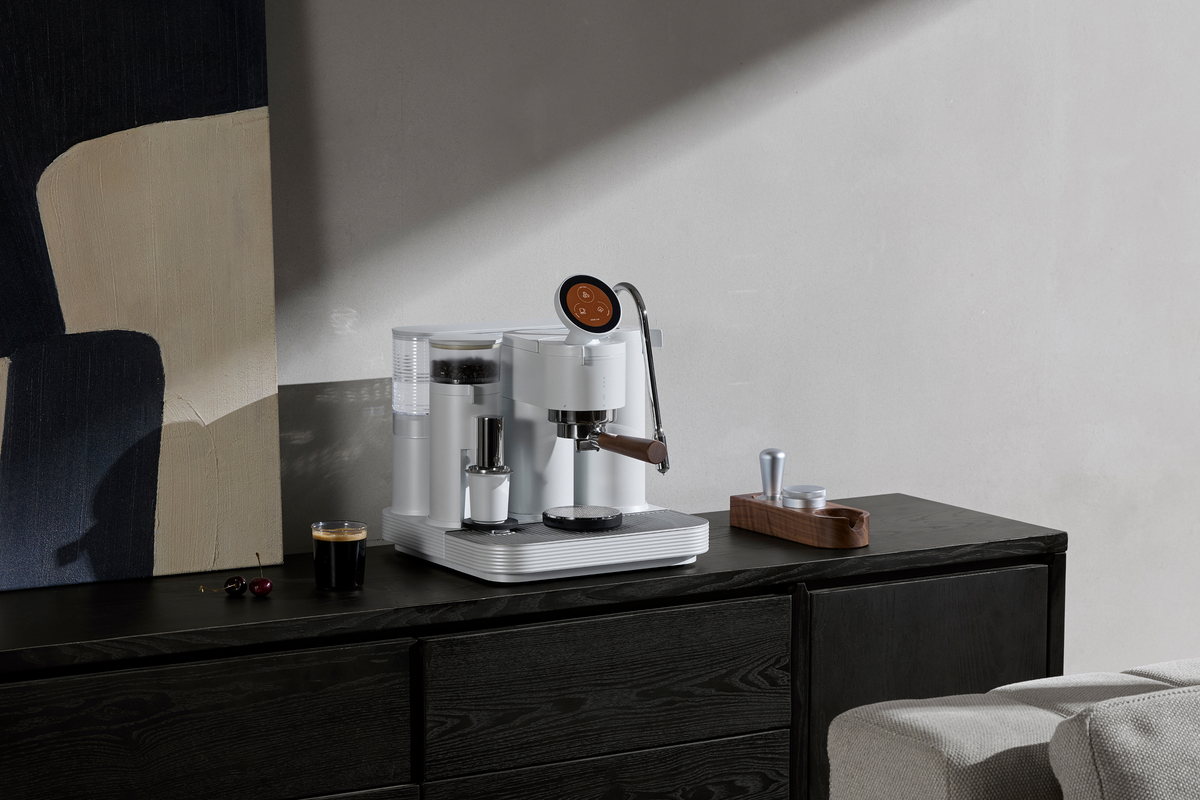 White Meraki espresso machine on a dark console in natural light