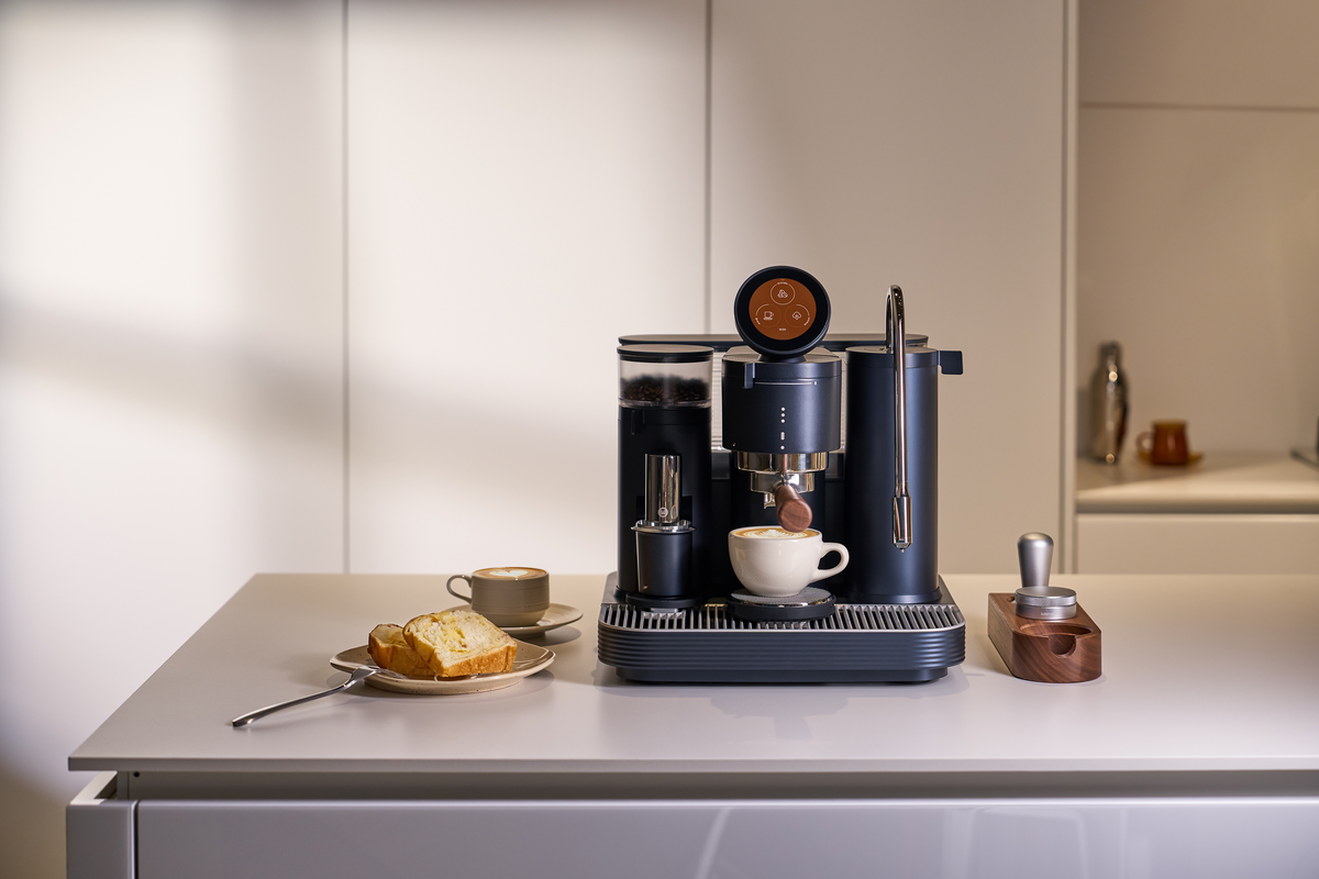 Black Meraki espresso machine with coffee accessories on a bright counter