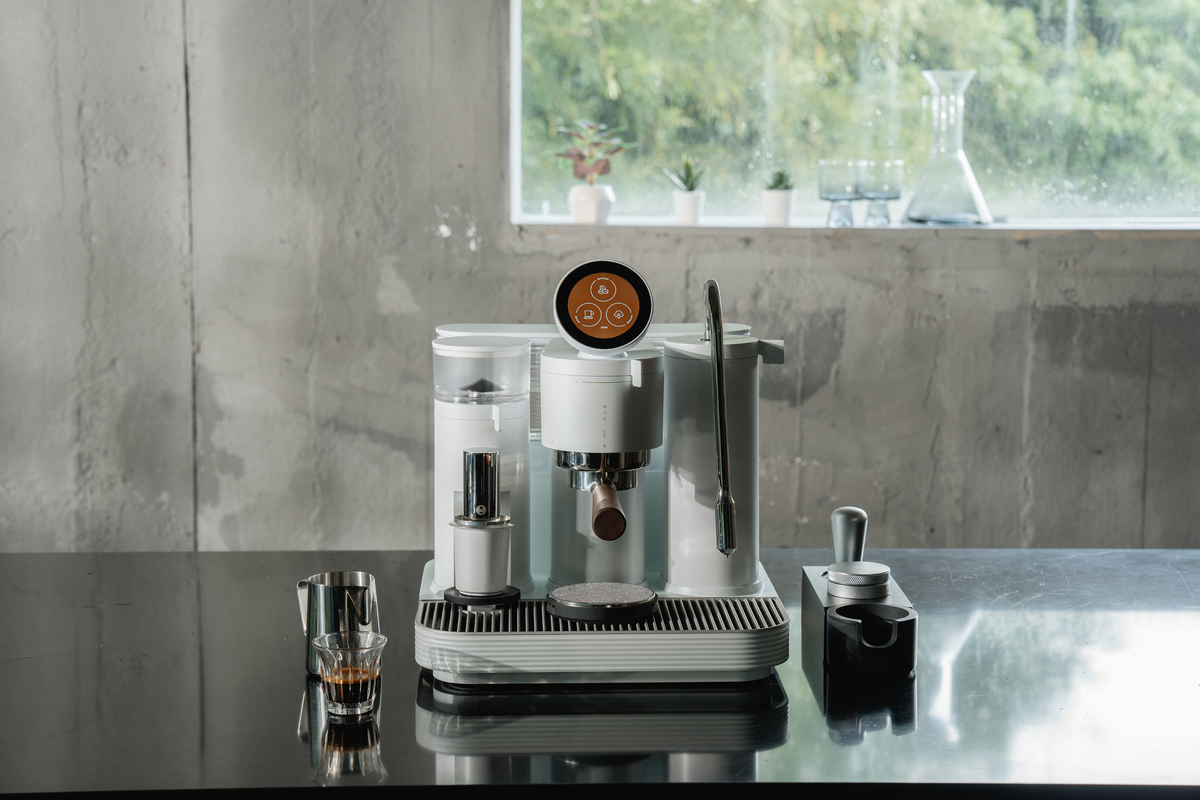 Front view of a white Meraki espresso machine beside a window