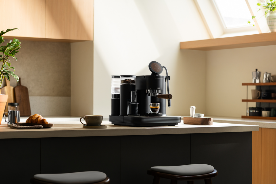 Black Meraki espresso machine on a kitchen island beneath a skylight