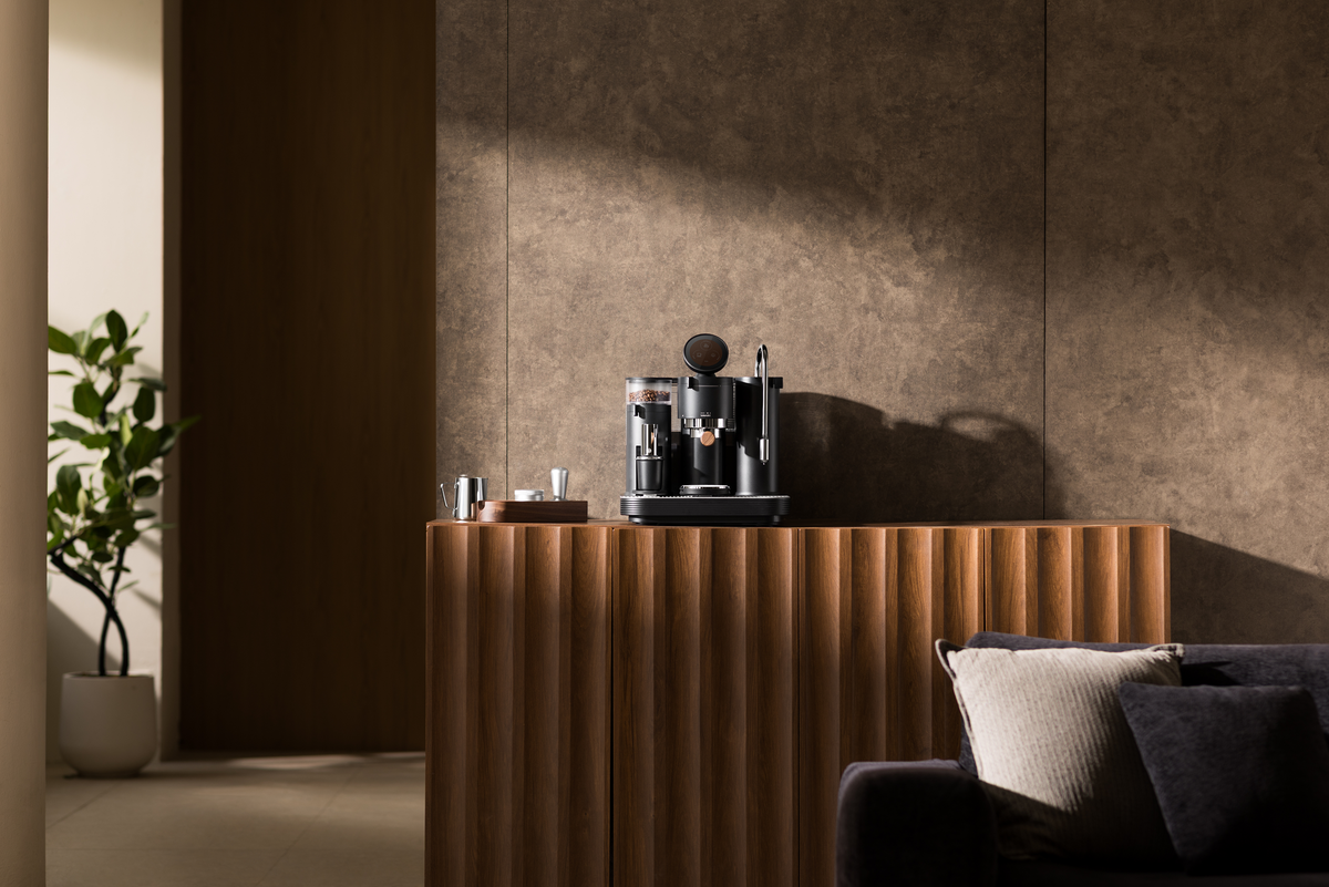 Black Meraki espresso machine on a wooden console in a home interior