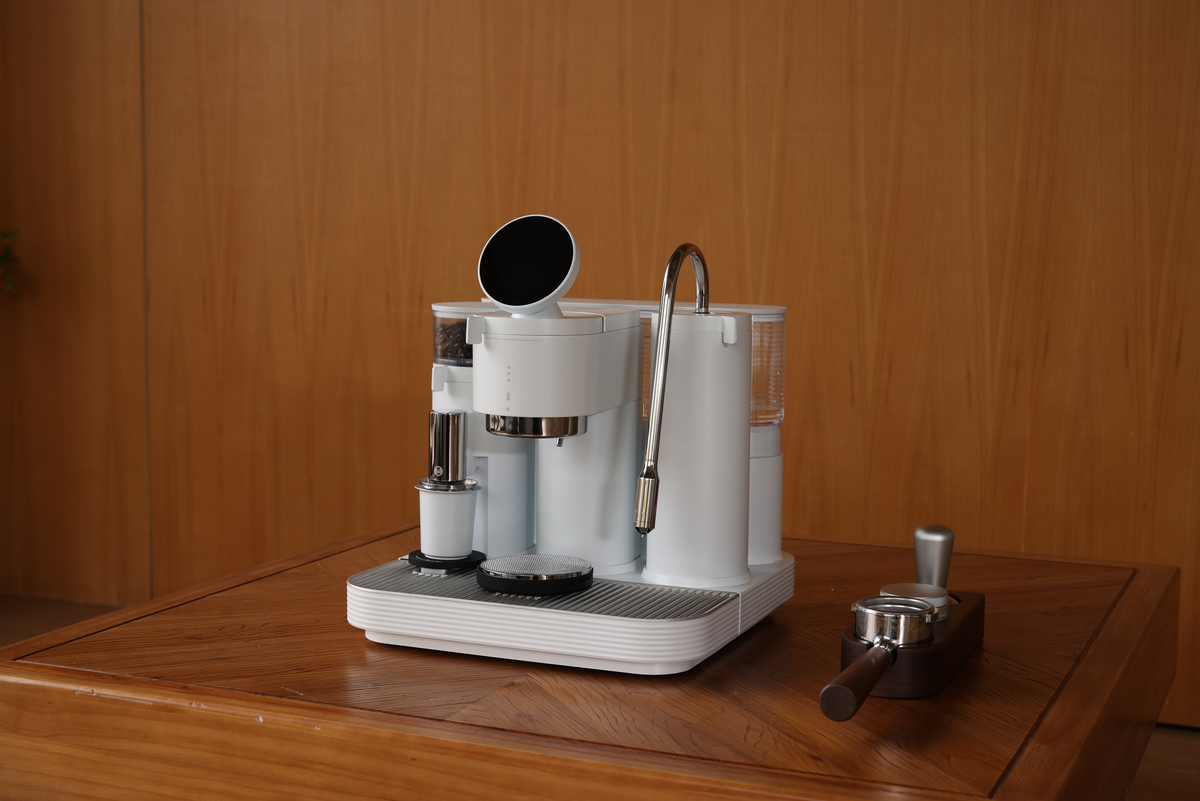 White Meraki espresso machine against a wooden wall