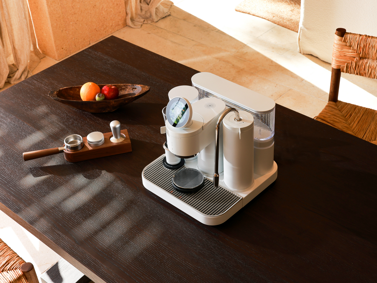 1. White Meraki espresso machine on a wooden table beside a portafilter, distributor, and tamper.
