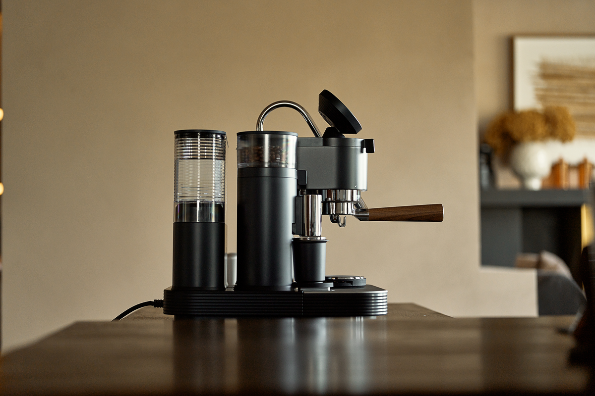 Side view of a black Meraki espresso machine on a wooden counter