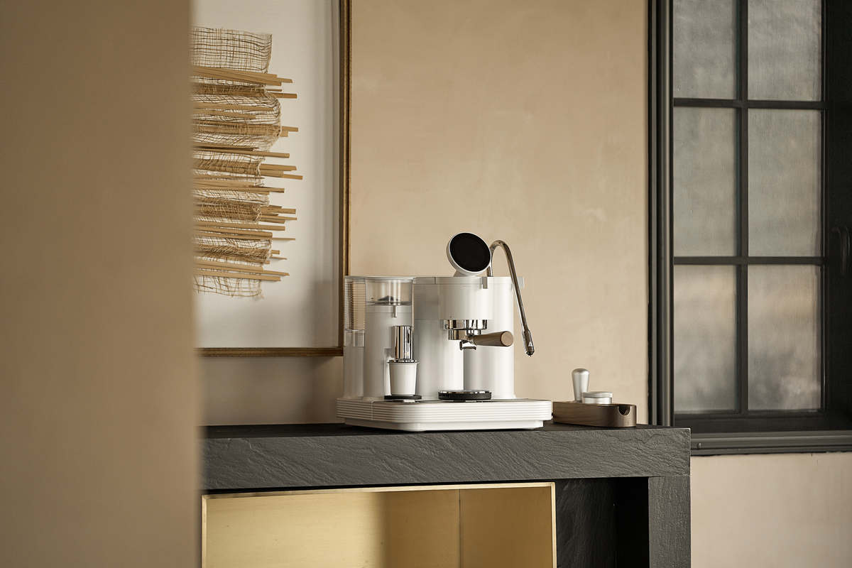 White Meraki espresso machine on a counter in a green kitchen