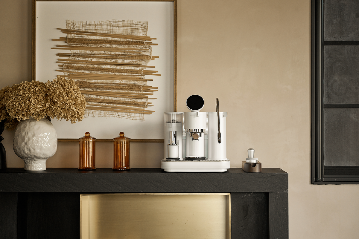 White Meraki espresso machine arranged with flowers on a kitchen counter