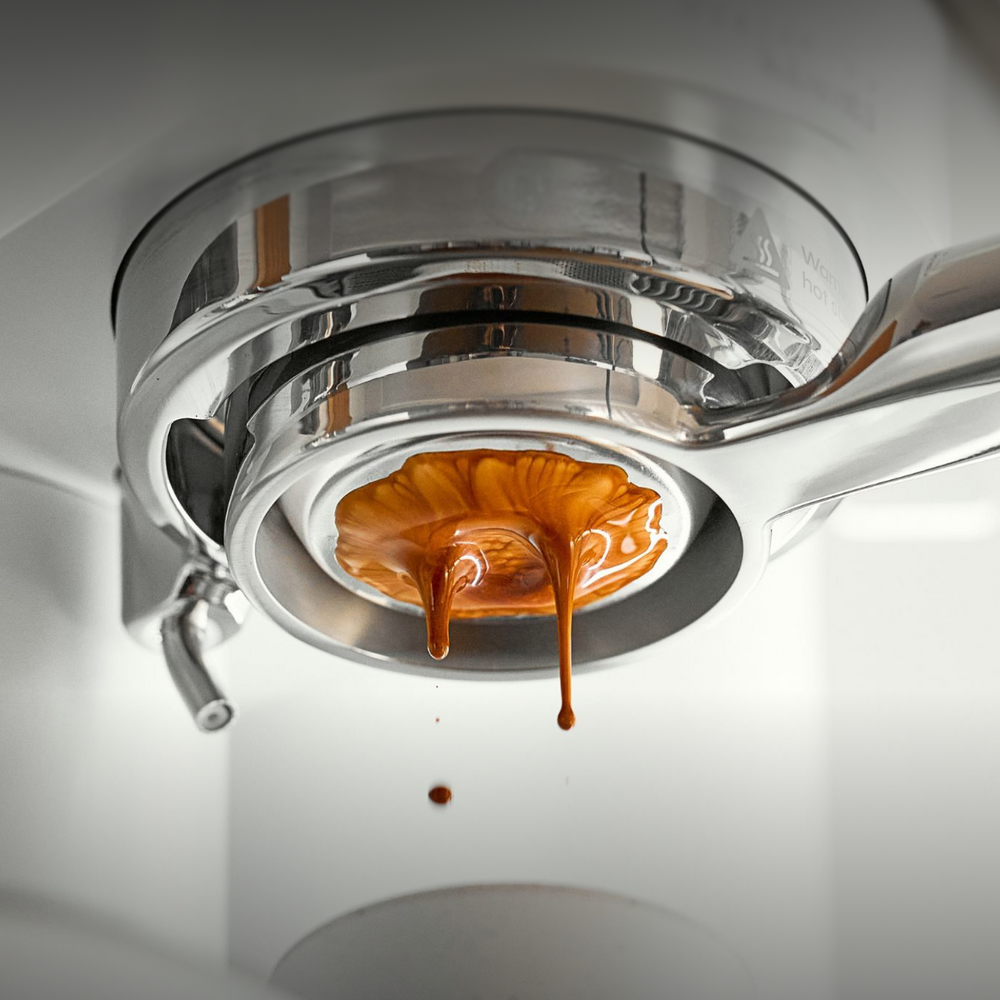 Espresso flowing unevenly through a bottomless portafilter during extraction