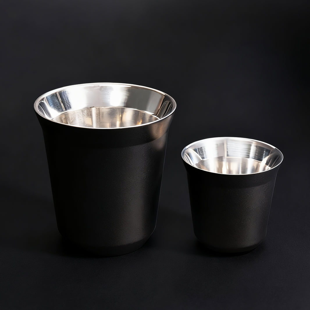 Double-walled stainless steel espresso and latte cups with black exterior and brushed metal interior.