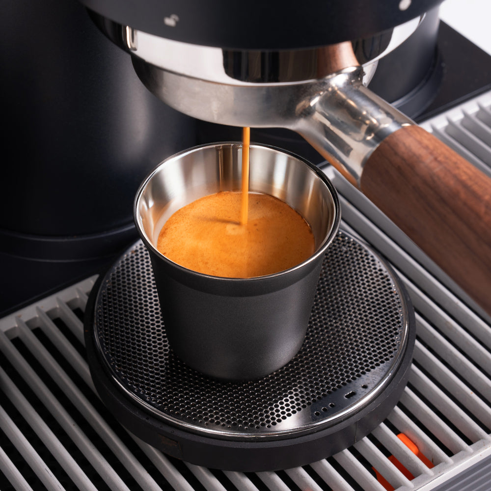 Fresh espresso pouring into a black Meraki cup