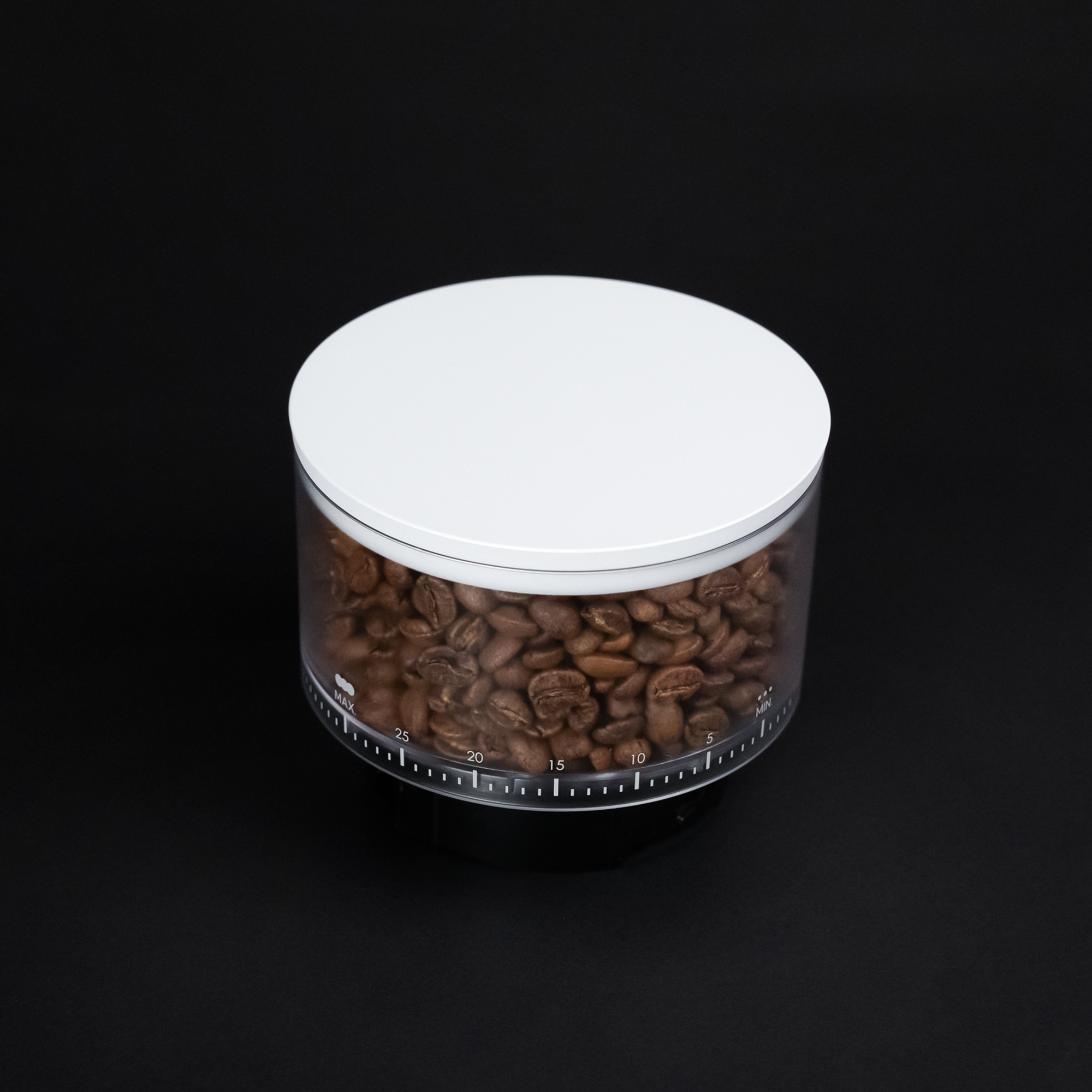 Transparent coffee bean container with white lid, measurement markings, filled with roasted beans on black background