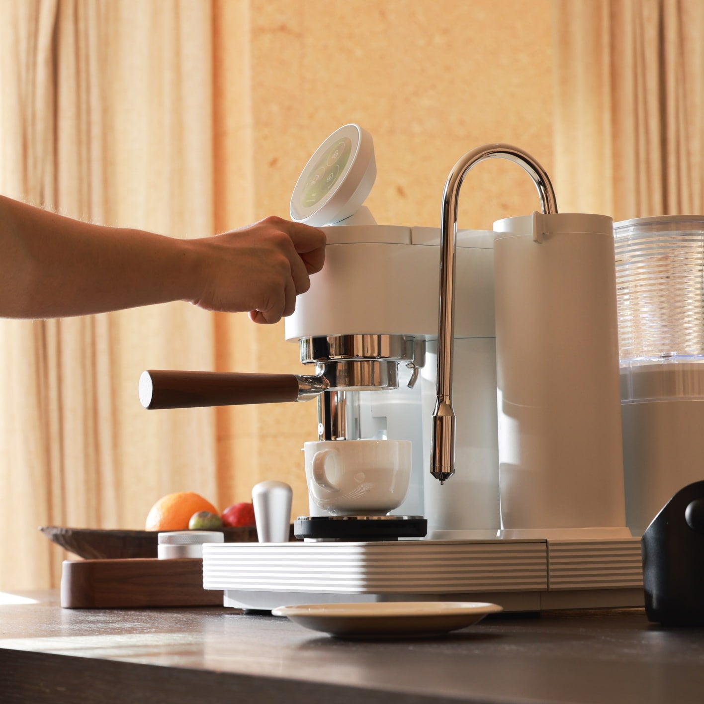 White Meraki espresso machine with touchscreen, walnut-handled portafilter and chrome steam wand in a home kitchen