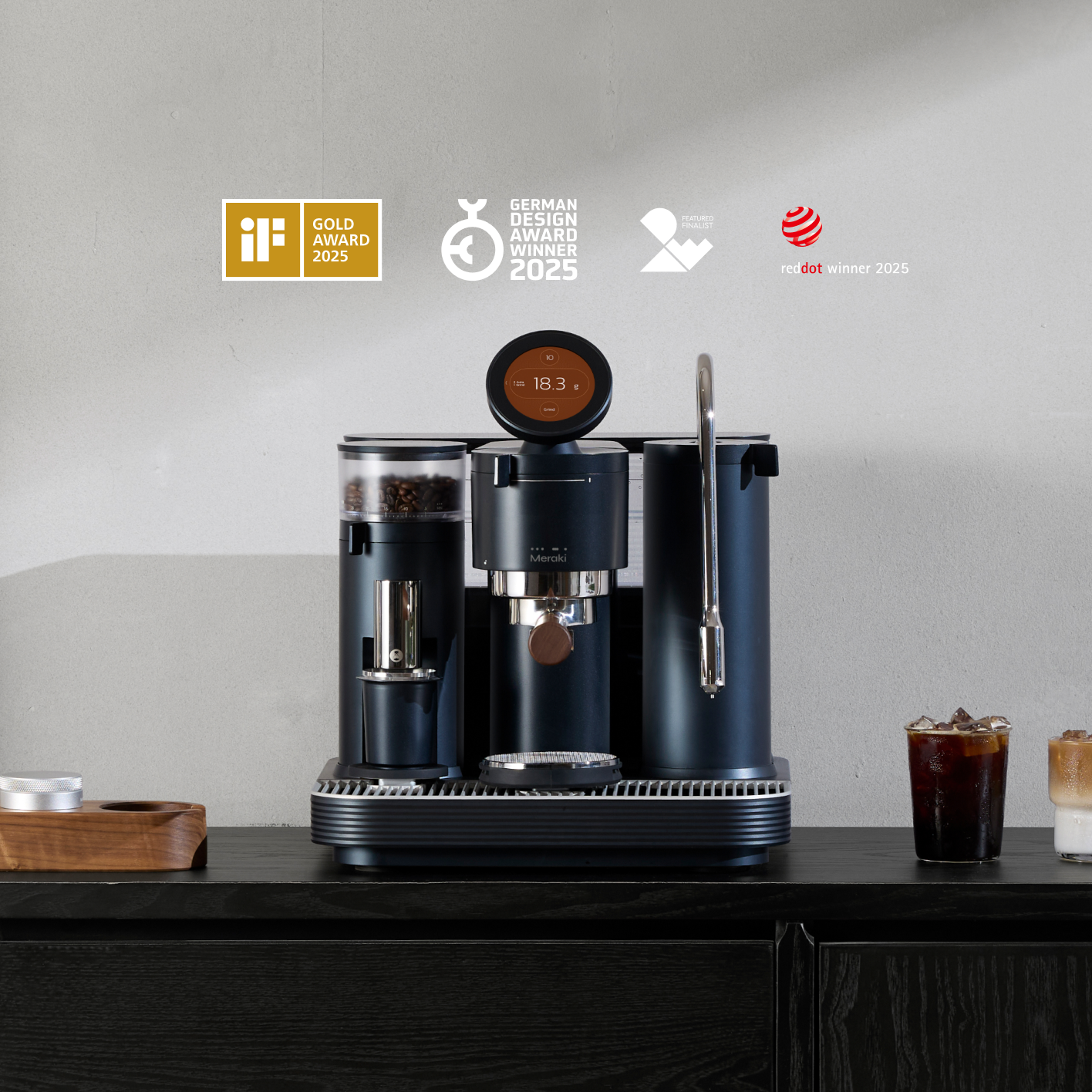 Meraki professional espresso machine with award logos and iced coffee on a black counter