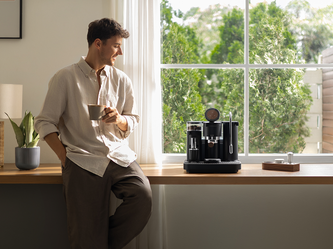 Person making espresso at home next to a bright window