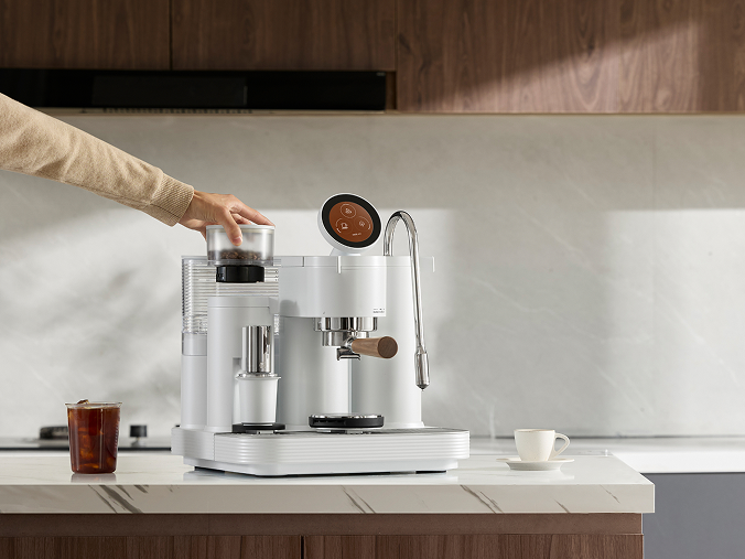 Person sitting at a table with Meraki espresso machine, exploring settings
